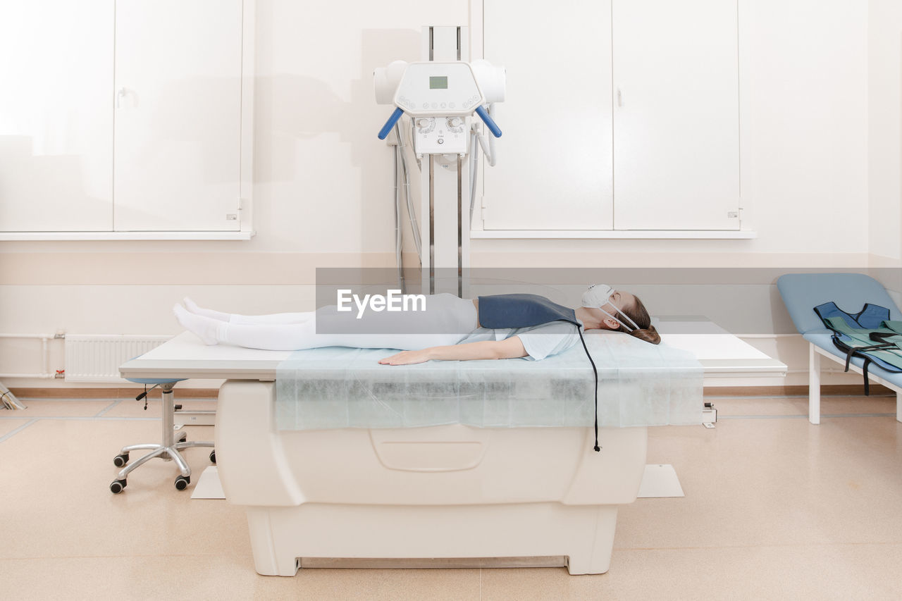Doctor taking x-ray of patient lying on gurney. hospital radiology room. x-ray machine