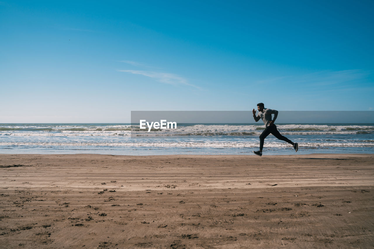 Full length of man running on beach against sky