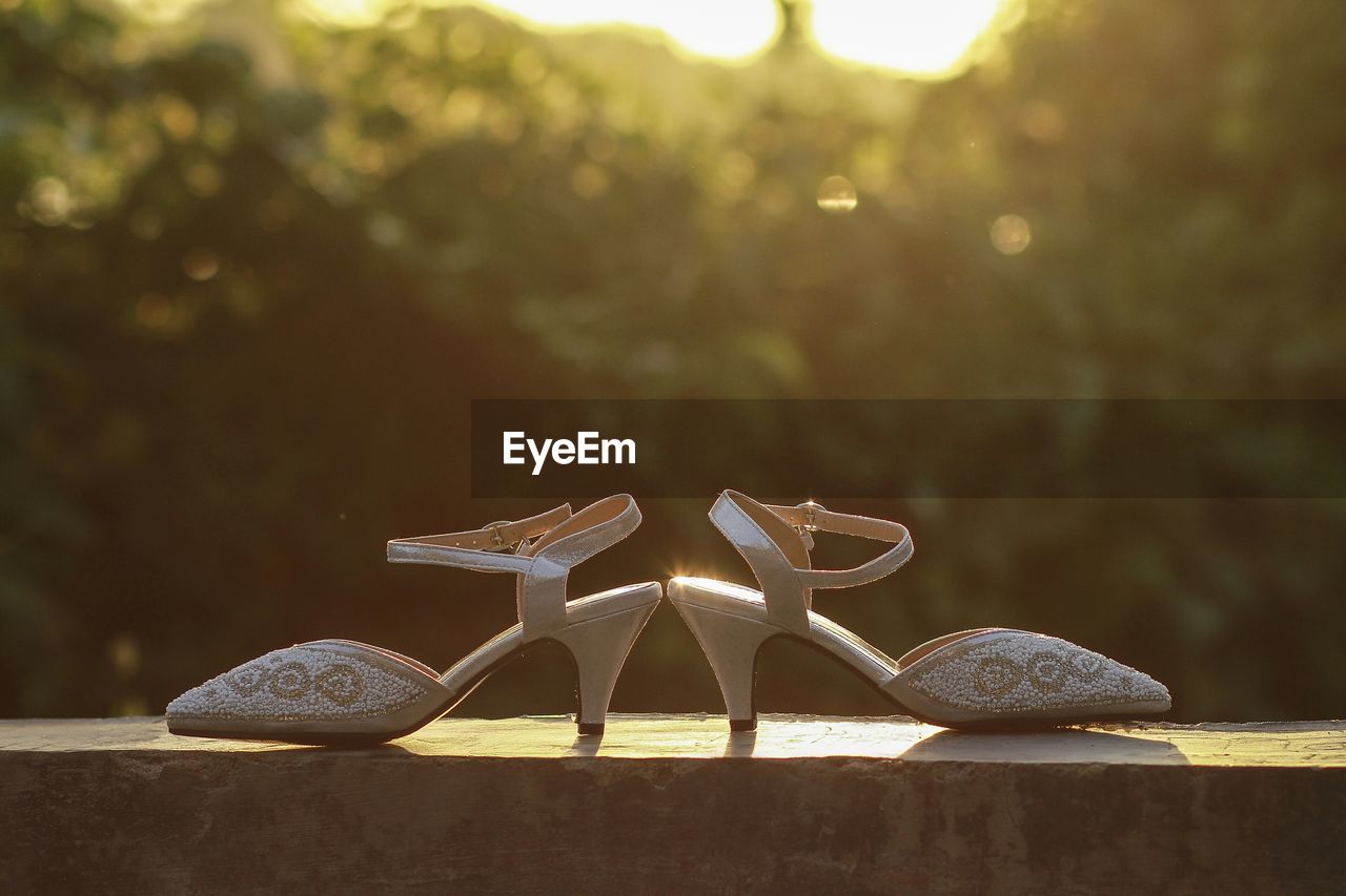 CLOSE-UP OF SHOES ON WOODEN TABLE AGAINST ROCK