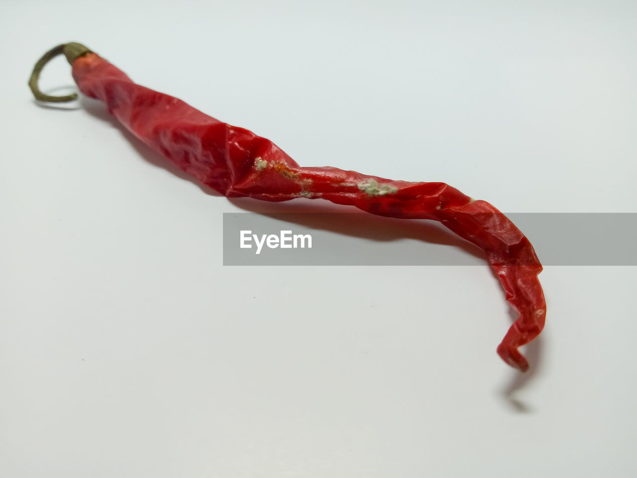 CLOSE-UP OF RED CHILI PEPPERS ON WHITE BACKGROUND