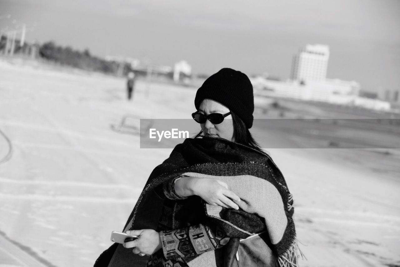 Woman wearing sunglasses while standing on street during winter