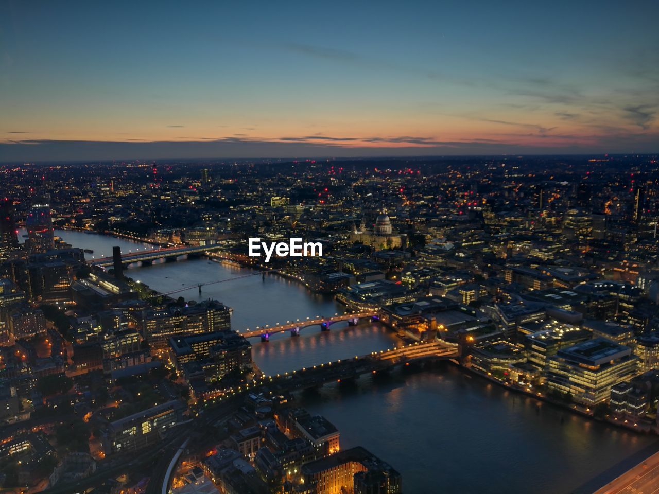 High angle view of city lit up at sunset