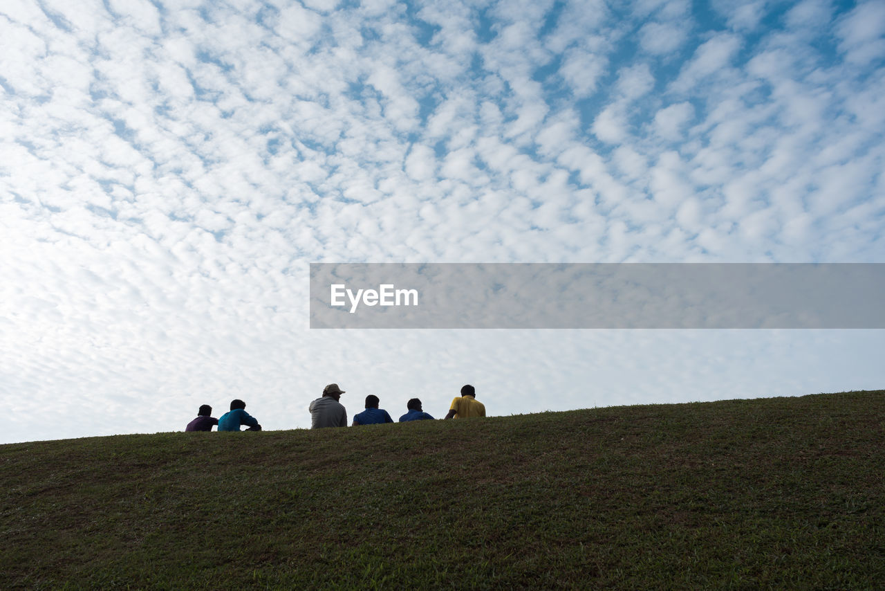 TOURISTS ON FIELD AGAINST SKY