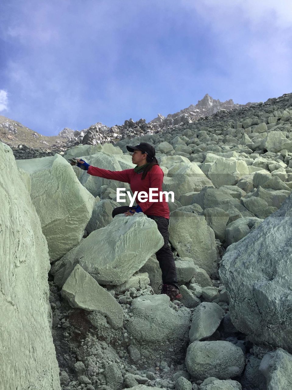 SIDE VIEW OF YOUNG MAN SITTING ON ROCK