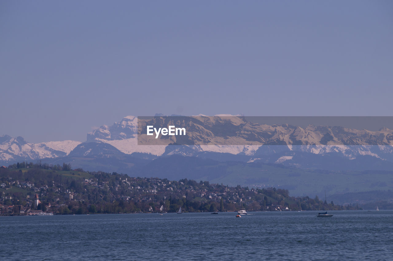 SEA BY MOUNTAINS AGAINST CLEAR SKY