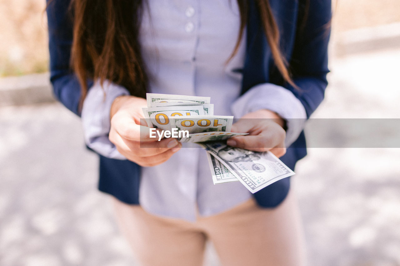 Midsection of woman holding banknotes