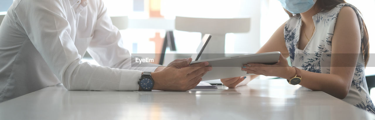 LOW ANGLE VIEW OF PEOPLE WORKING ON TABLE IN OFFICE