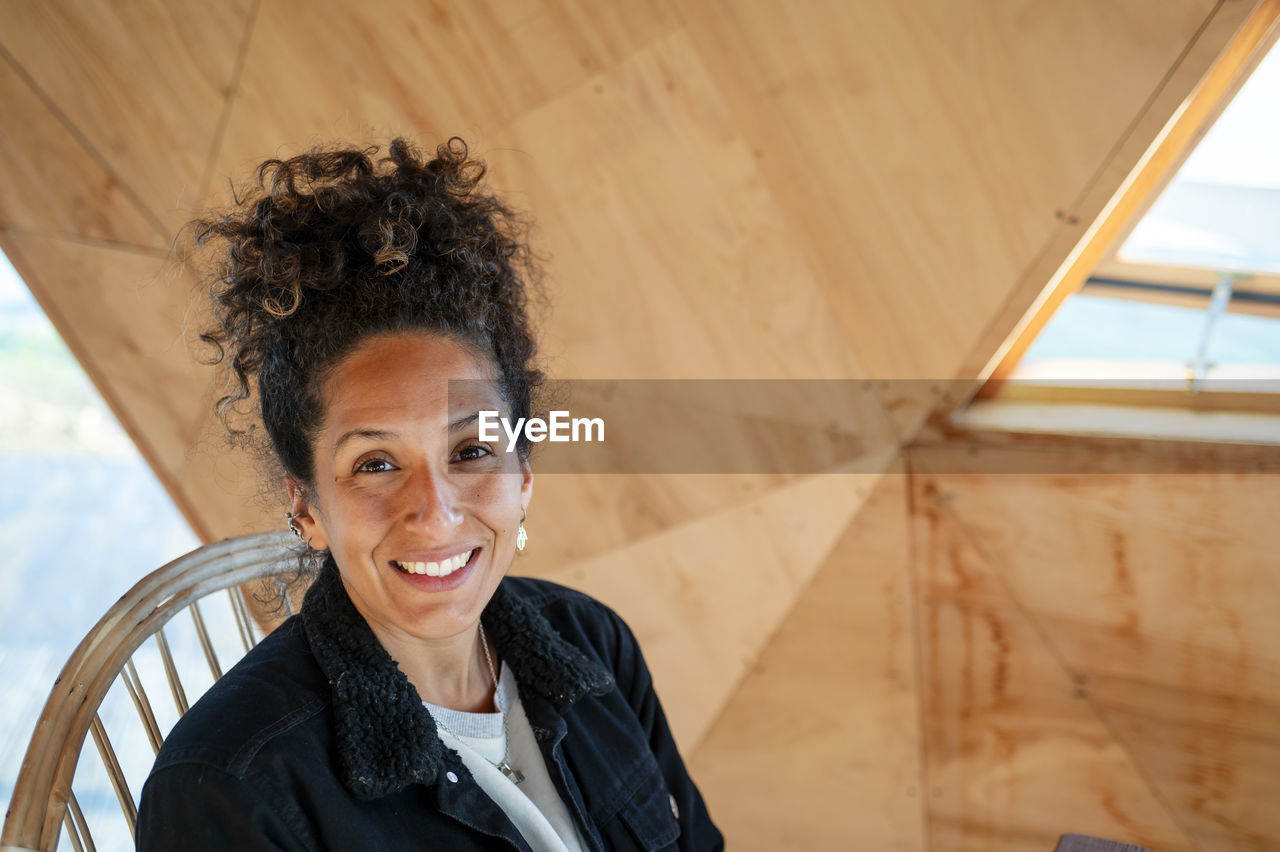 Happy latin woman smiling while sitting indoors.