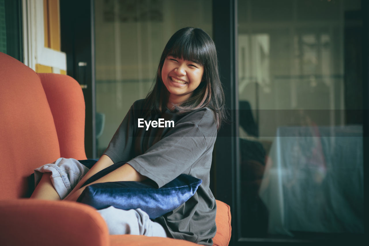 Asian teenager toothy smiling face ,relaxing in home living room