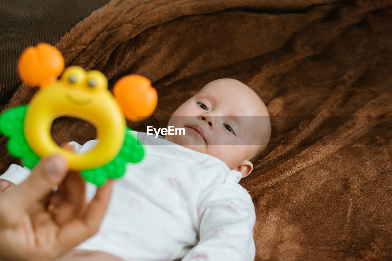 First rattle toy for baby. rattles and teethers, teething toys. cute newborn baby girl looking at
