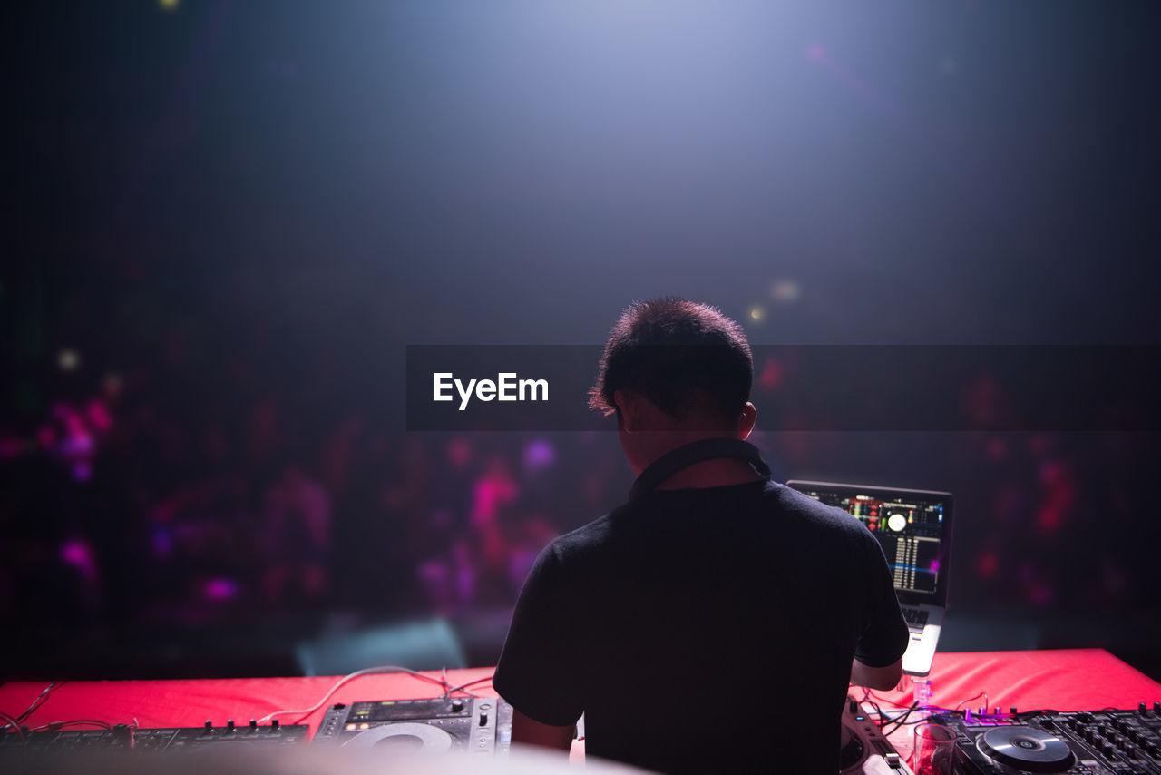 Rear view of man playing music on sound mixer