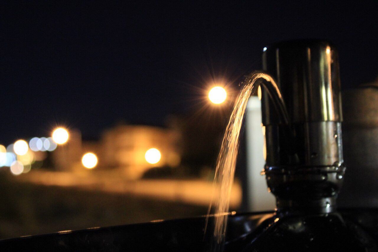 Close-up of water spraying from faucet at night