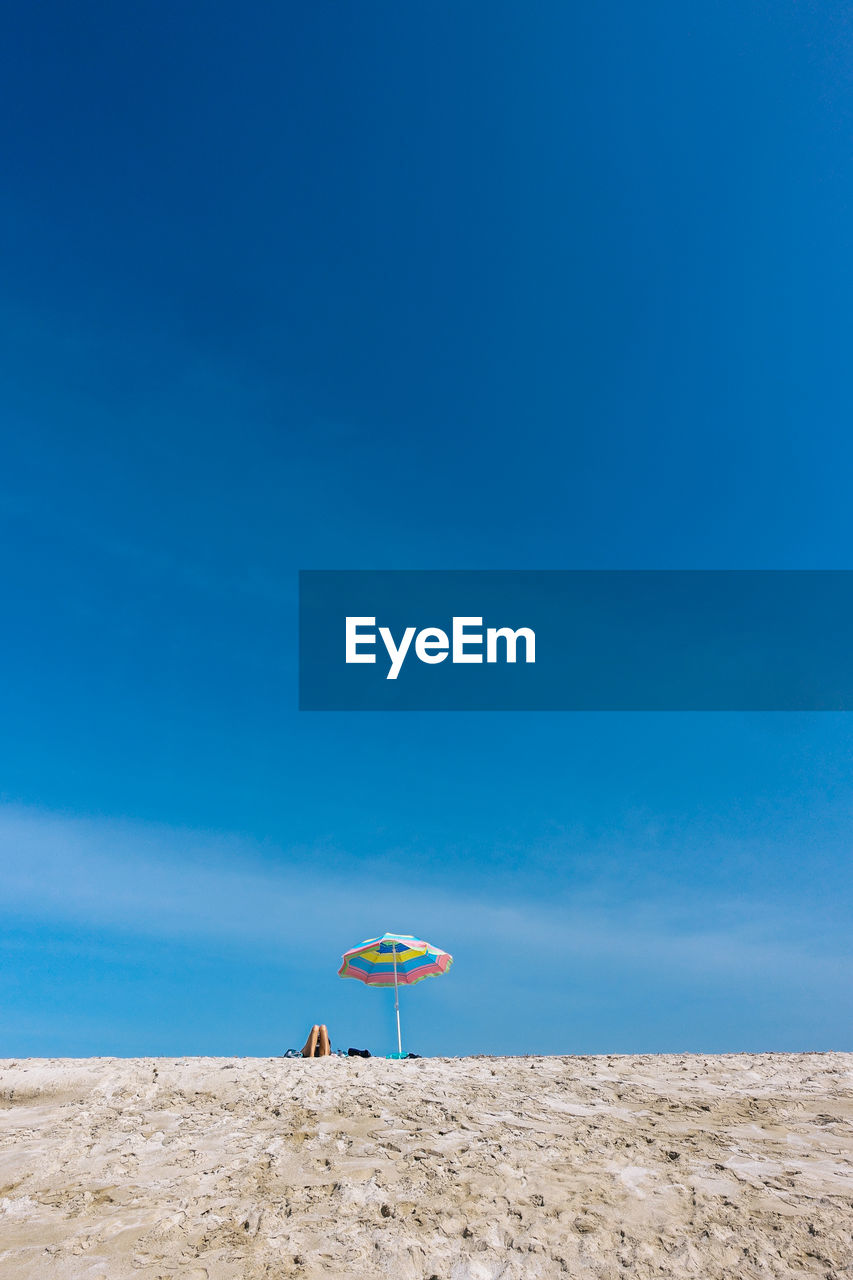 Parasol at beach against blue sky