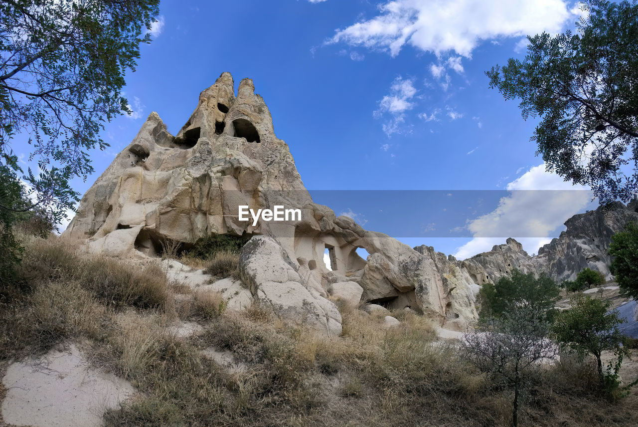 sky, rock, plant, tree, nature, scenics - nature, travel destinations, wilderness, landscape, environment, land, beauty in nature, no people, cloud, history, mountain, travel, rock formation, architecture, the past, non-urban scene, tranquility, low angle view, outdoors, blue, geology, tourism, ancient, day, tranquil scene, formation, ruins, adventure, mountain range, physical geography, religion, valley, ancient history, desert