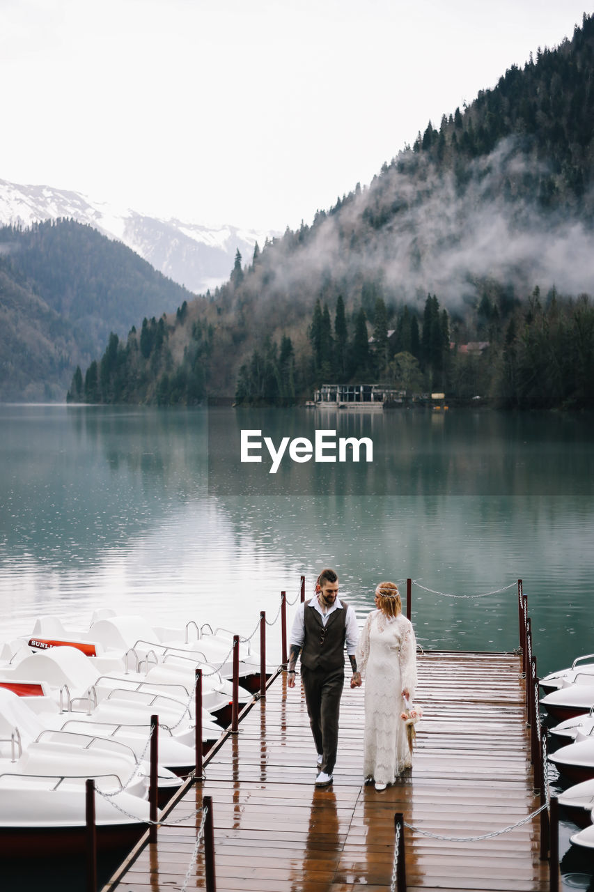 A happy couple in love and married embrace in nature by the lake and the misty mountains