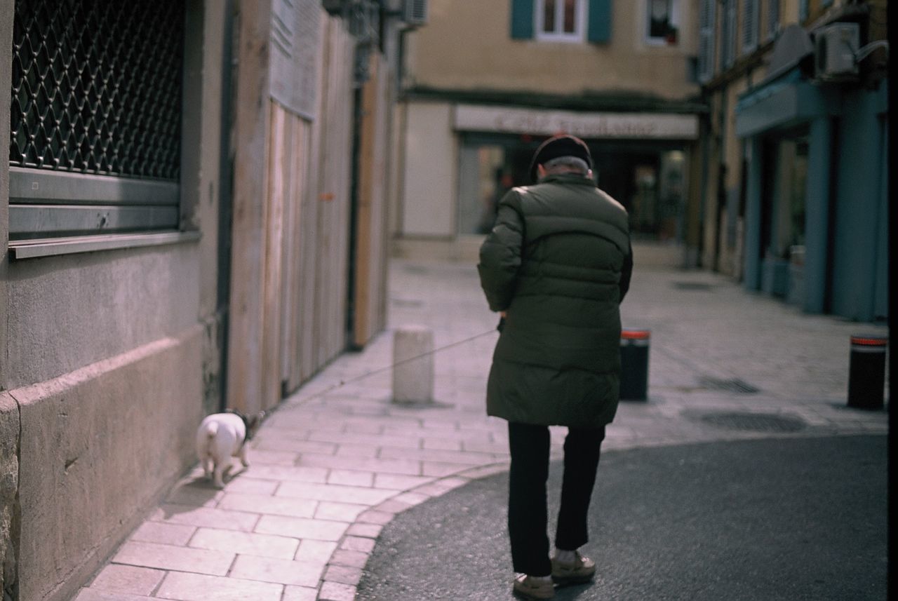 FULL LENGTH REAR VIEW OF WOMAN WALKING ON SIDEWALK