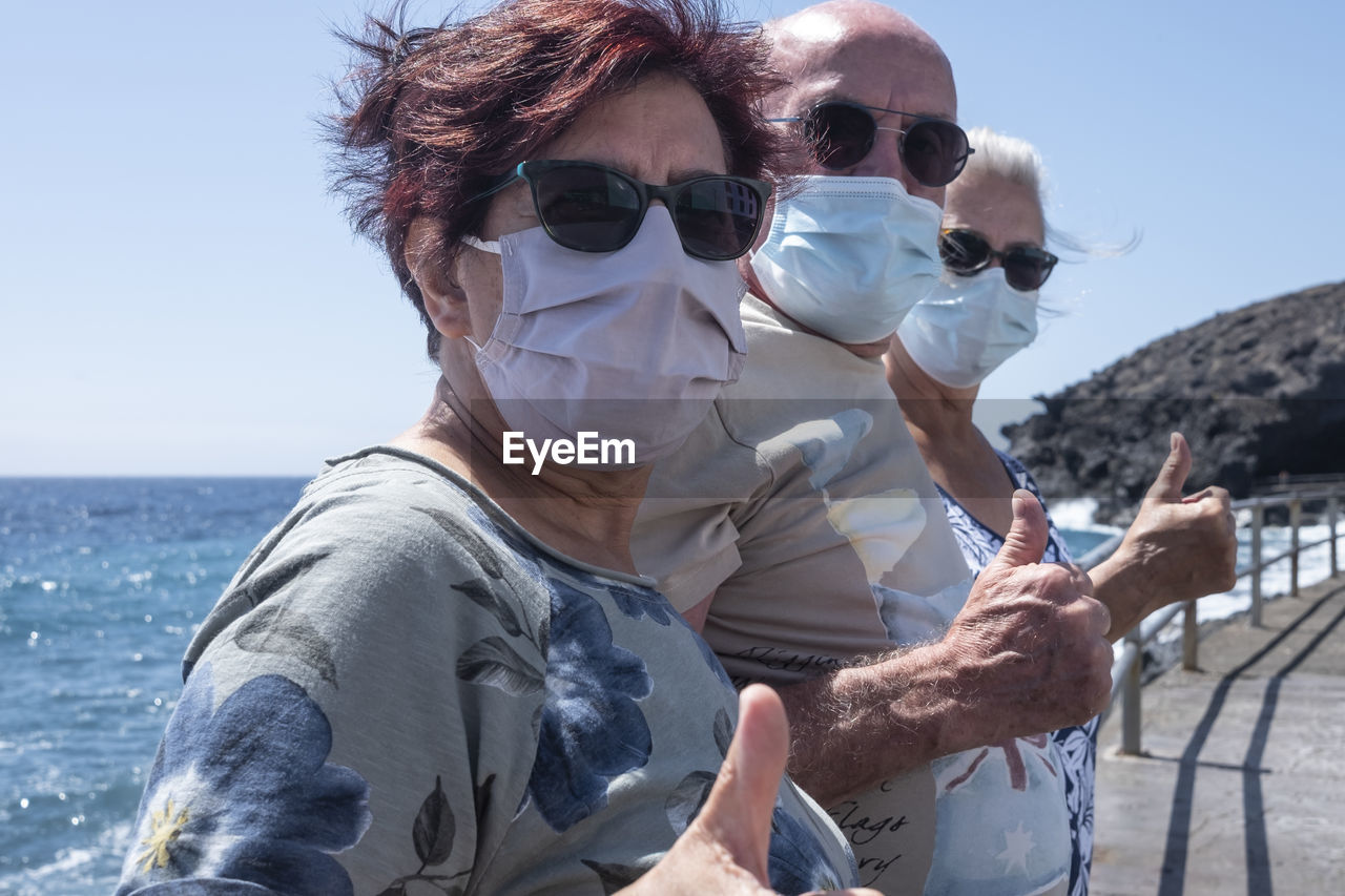 Portrait of smiling senior people gesturing against sea and sky