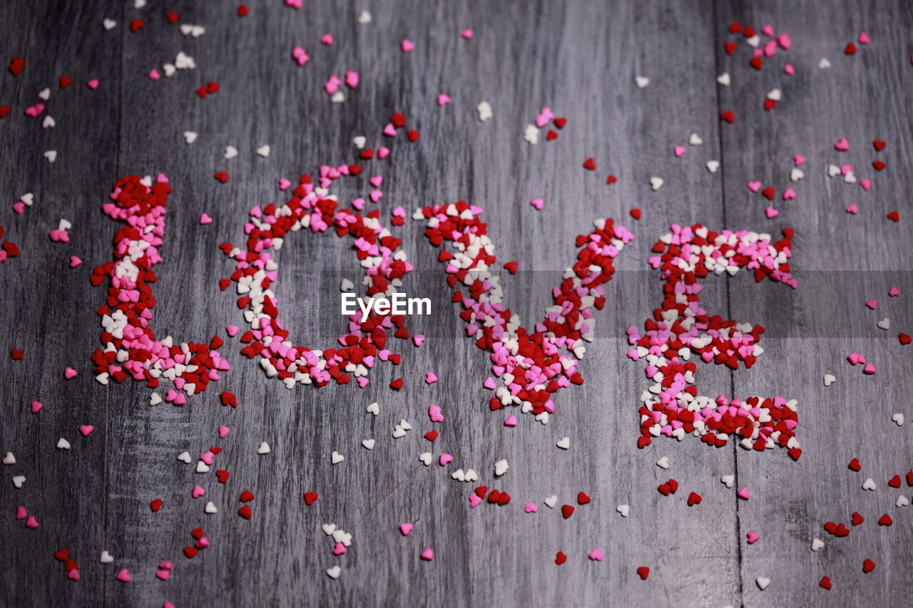 High angle view of love text made with heart shape confetti on table