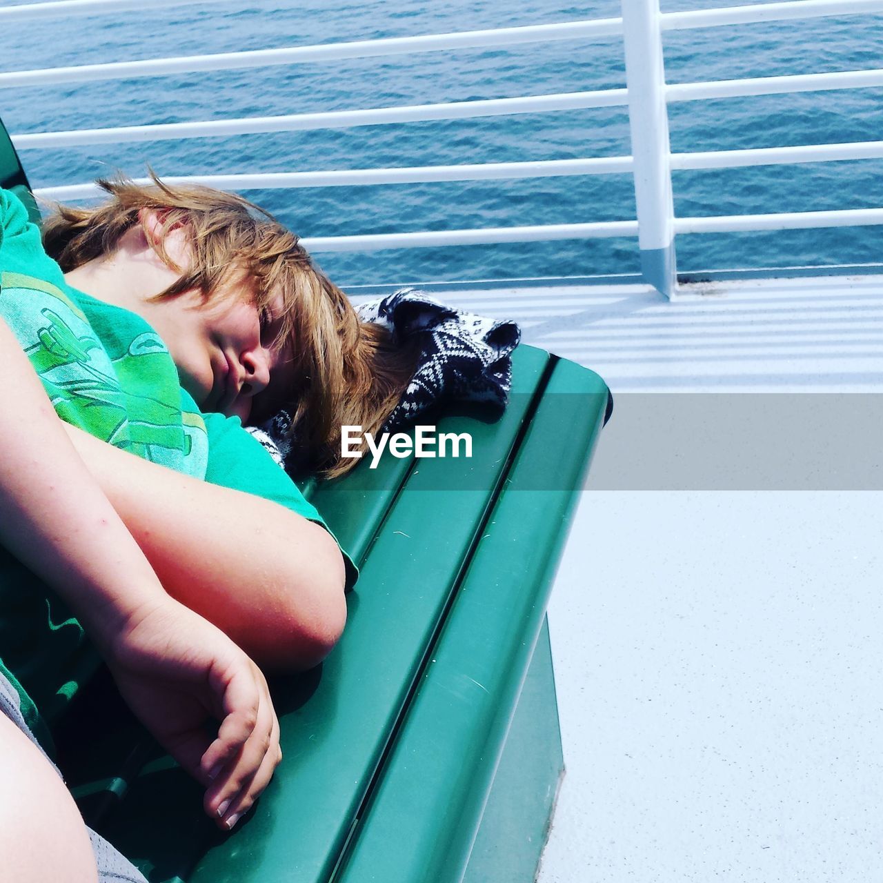 Boy sleeping on bench in boat