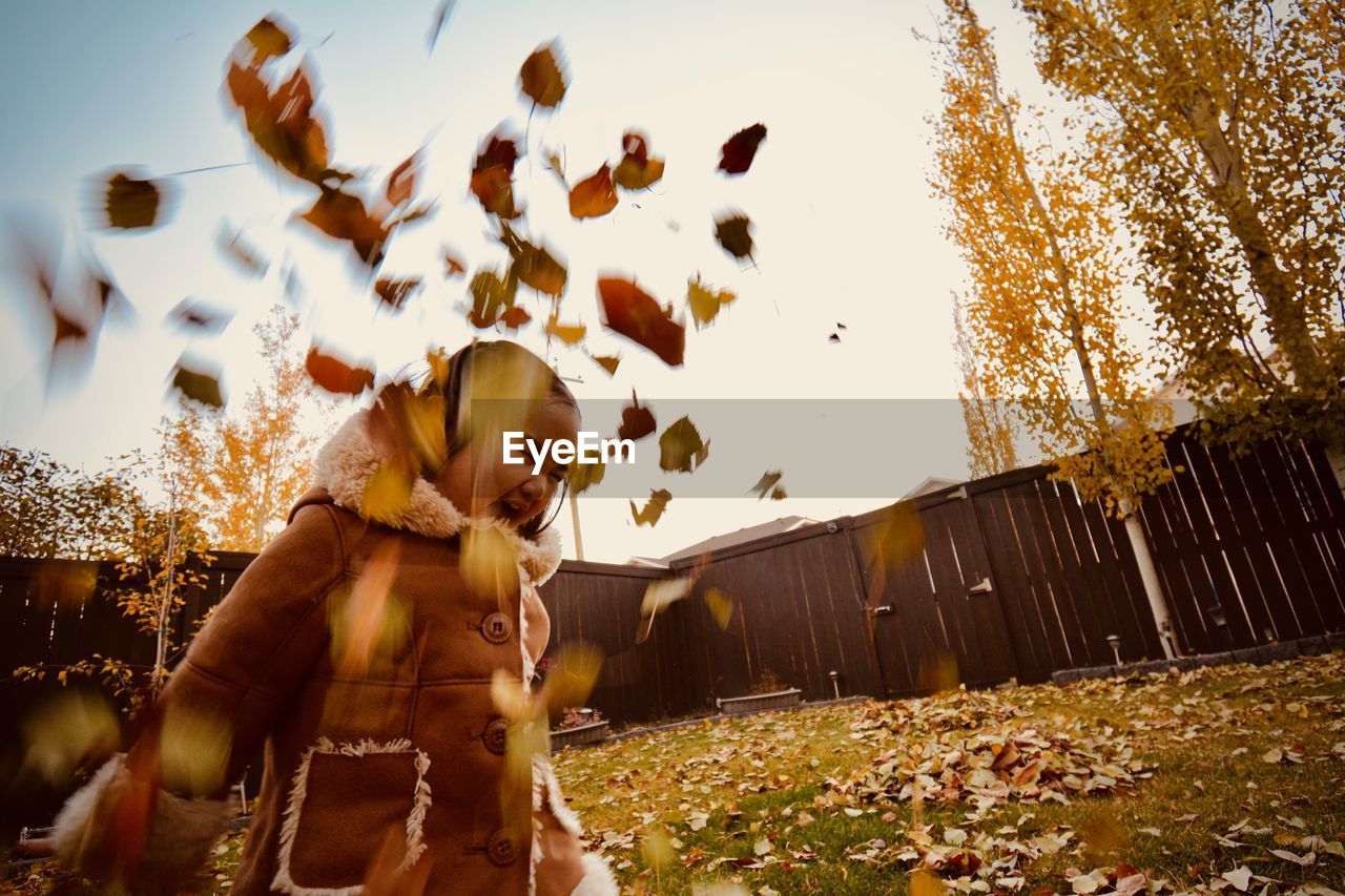 Cute girl throwing dry leaves during autumn