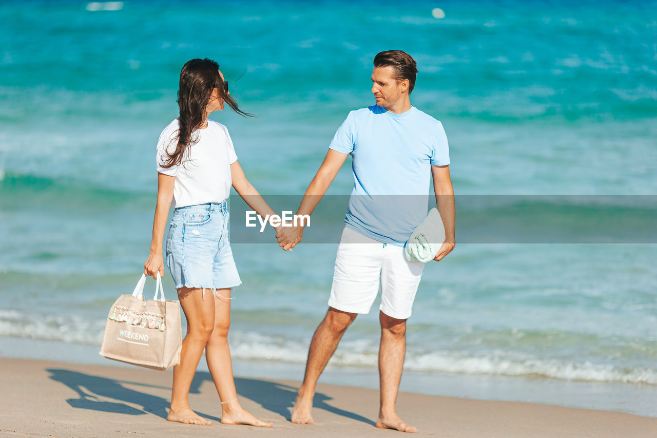 side view of mother and daughter walking at beach