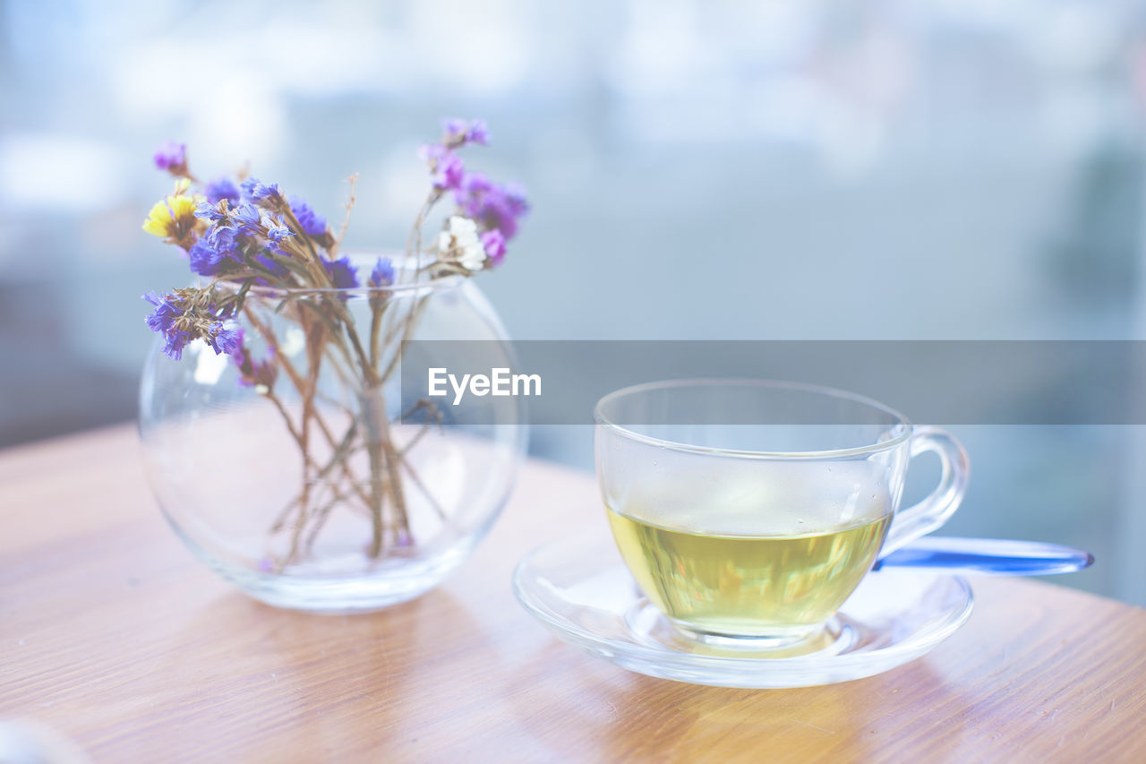 Close-up of herbal tea and flower pot on table at cafe