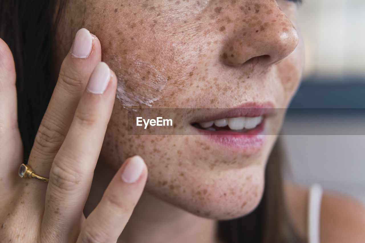 Hand of woman applying moisturizer on face