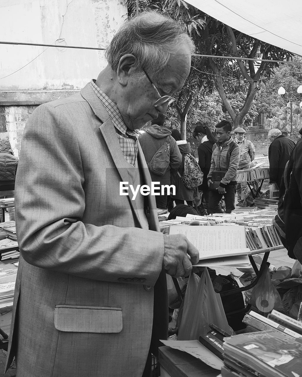 Senior man in suit holding book at market