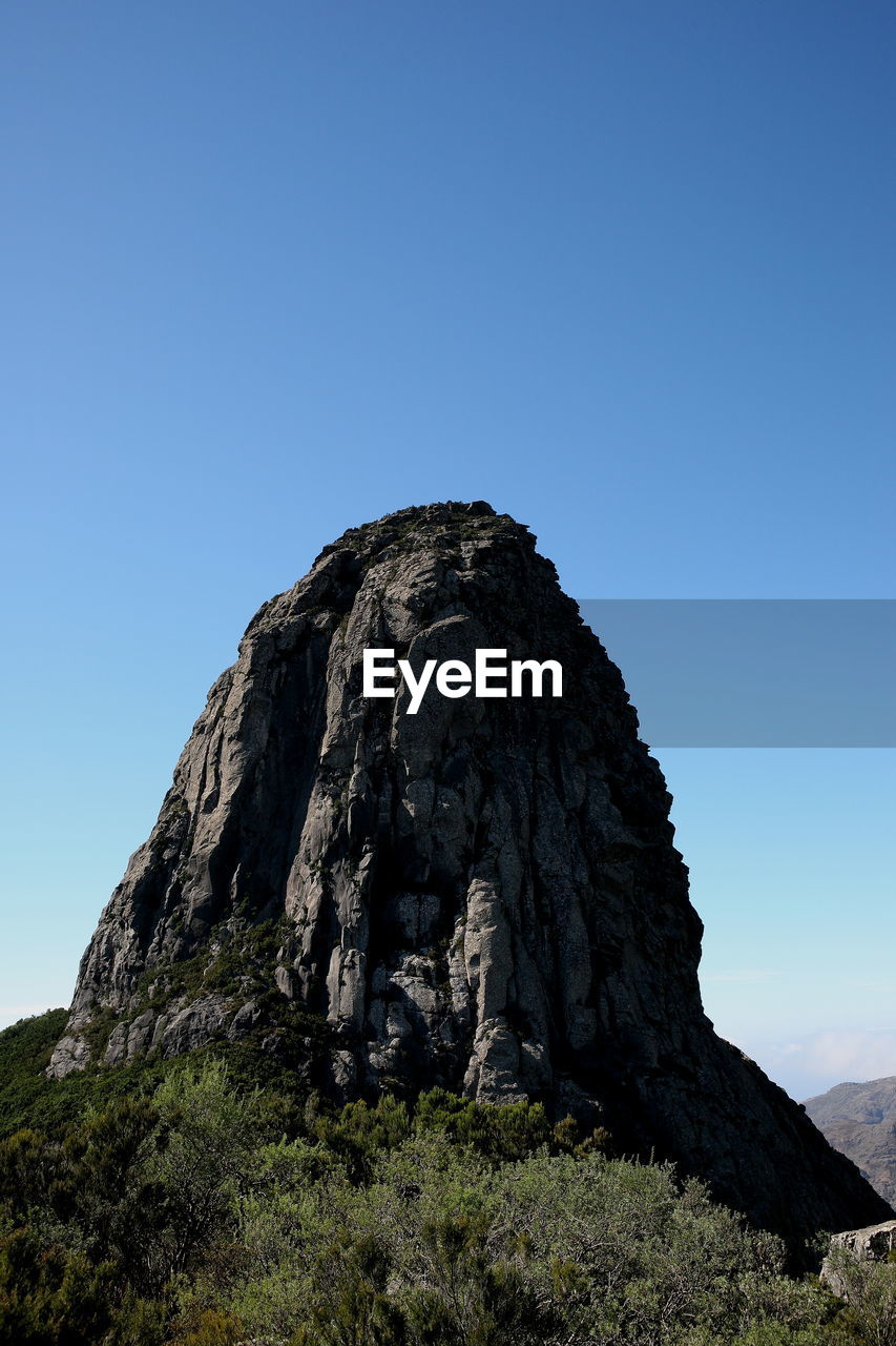 Low angle view of rock formations against clear blue sky