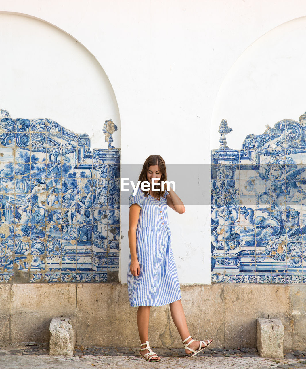 Full length of smiling woman standing against building wall