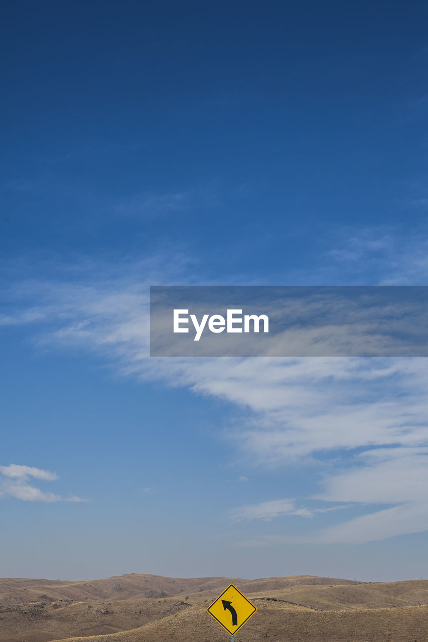 Road sign against by mountains against blue sky