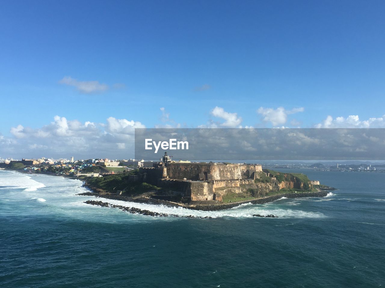 Buildings by sea against blue sky