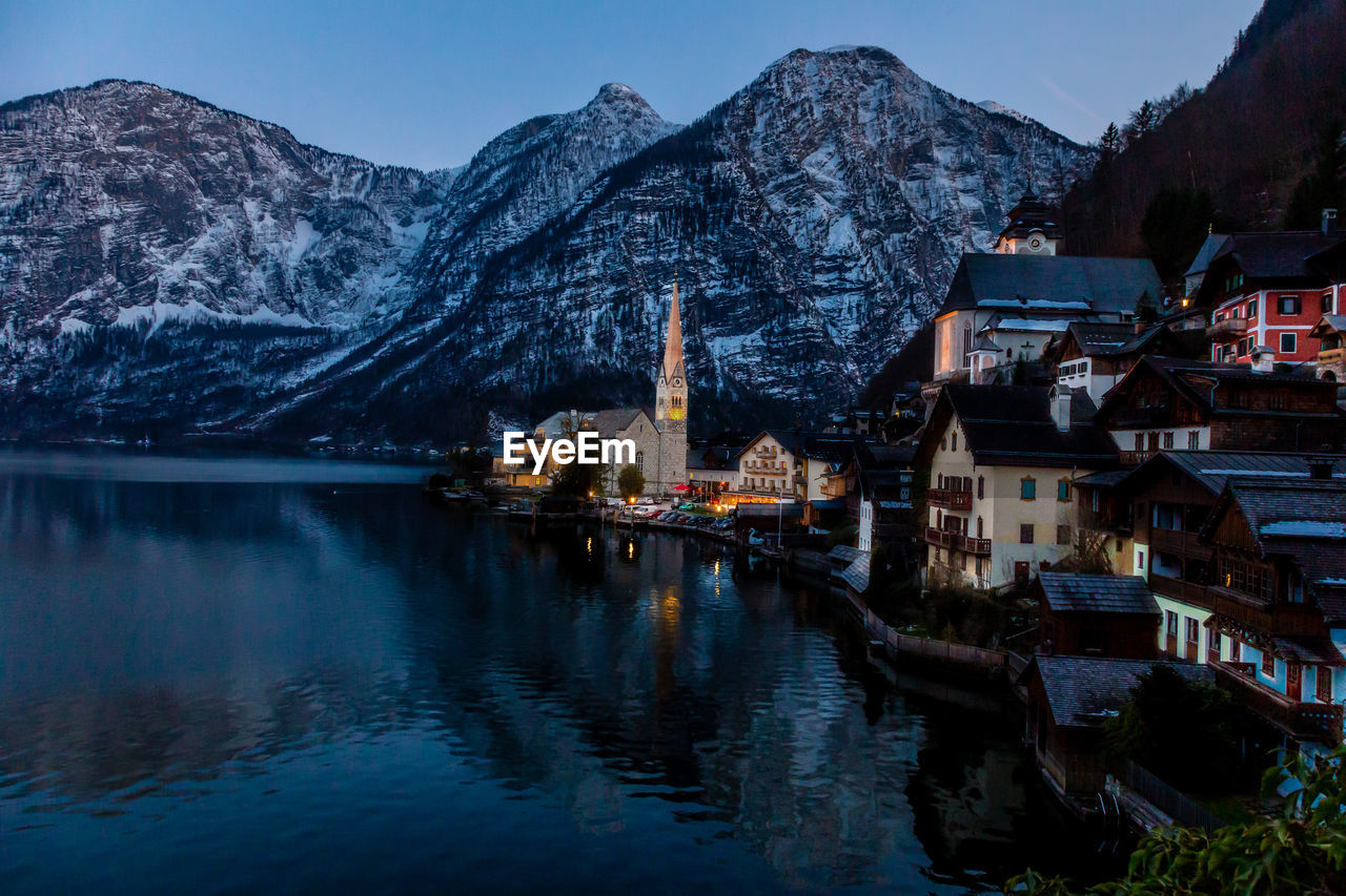 View of beautiful hallstatt lake and famous church during evening after sunset 
 with mountain range