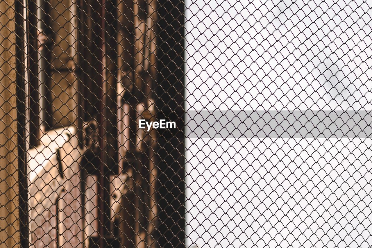 FULL FRAME SHOT OF CHAINLINK FENCE AGAINST BLURRED LANDSCAPE