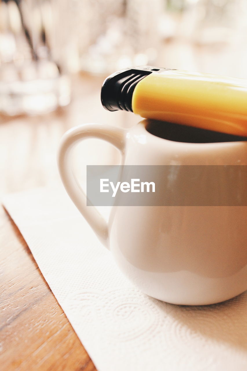 Close-up of coffee and cigarette lighter on table