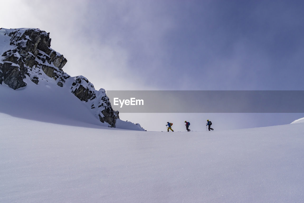 People skiing on snowcapped mountain against sky