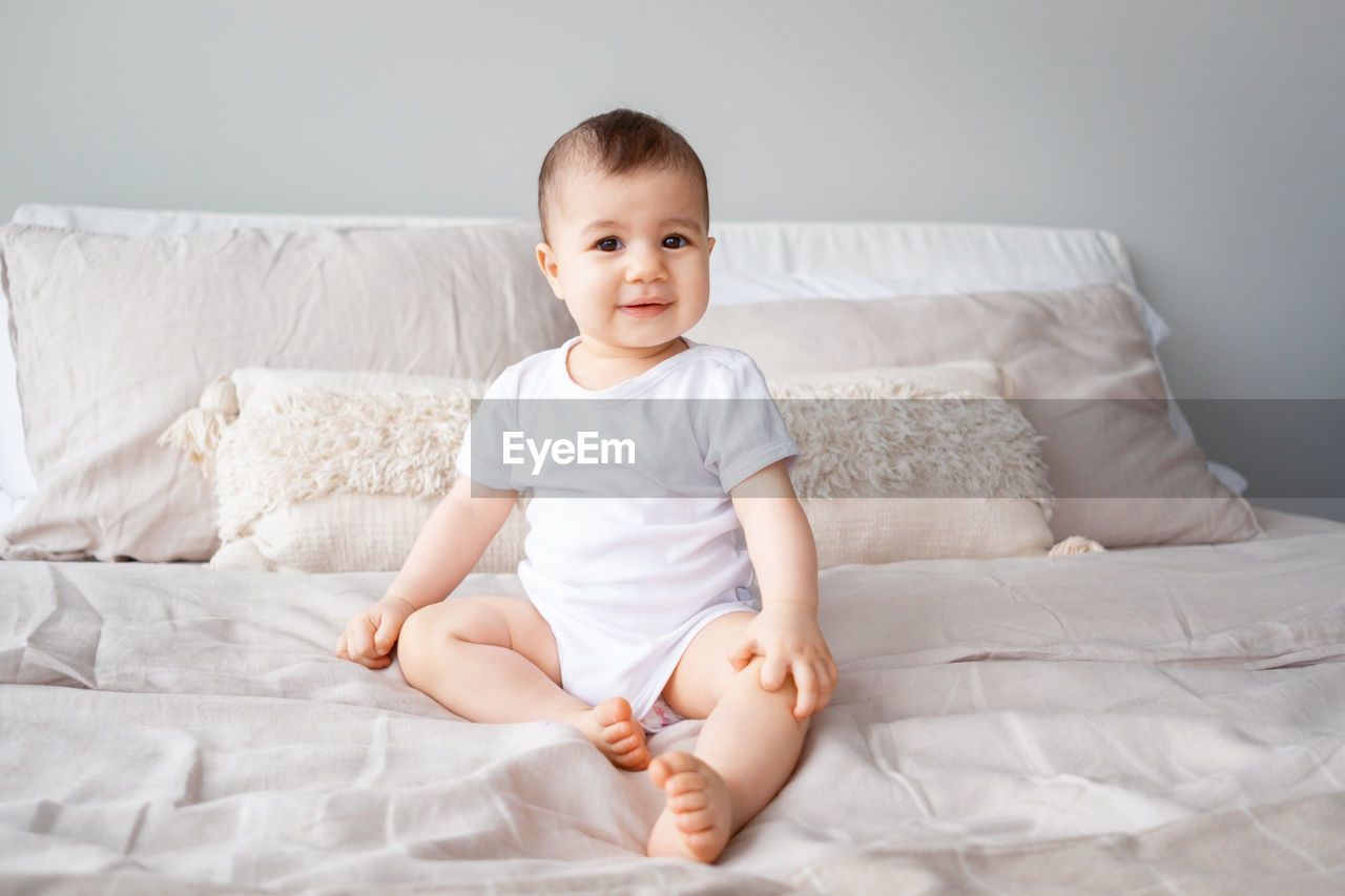 Portrait of smiling boy sitting on bed at home