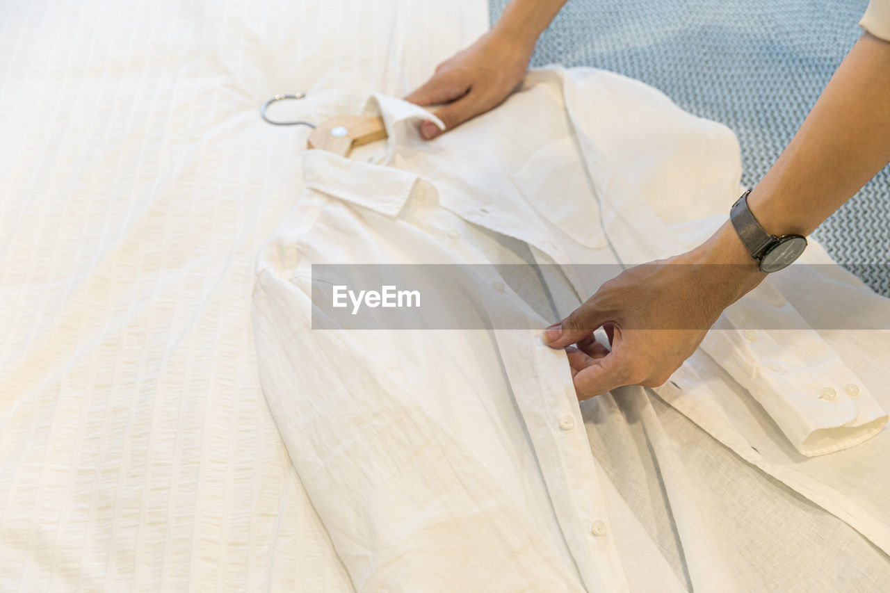 HIGH ANGLE VIEW OF WOMAN HAND ON BED IN BEDROOM