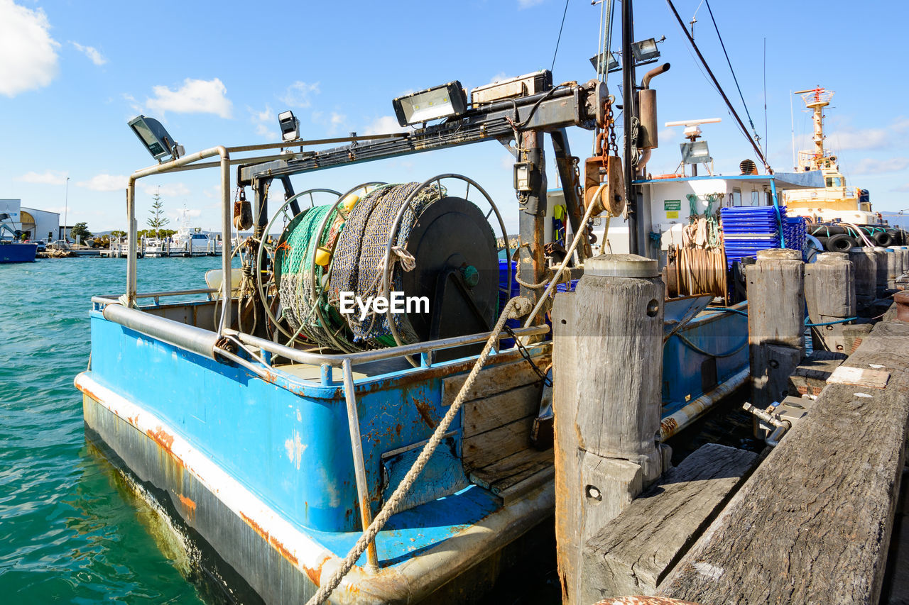 BOATS MOORED AT SEA AGAINST BLUE SKY