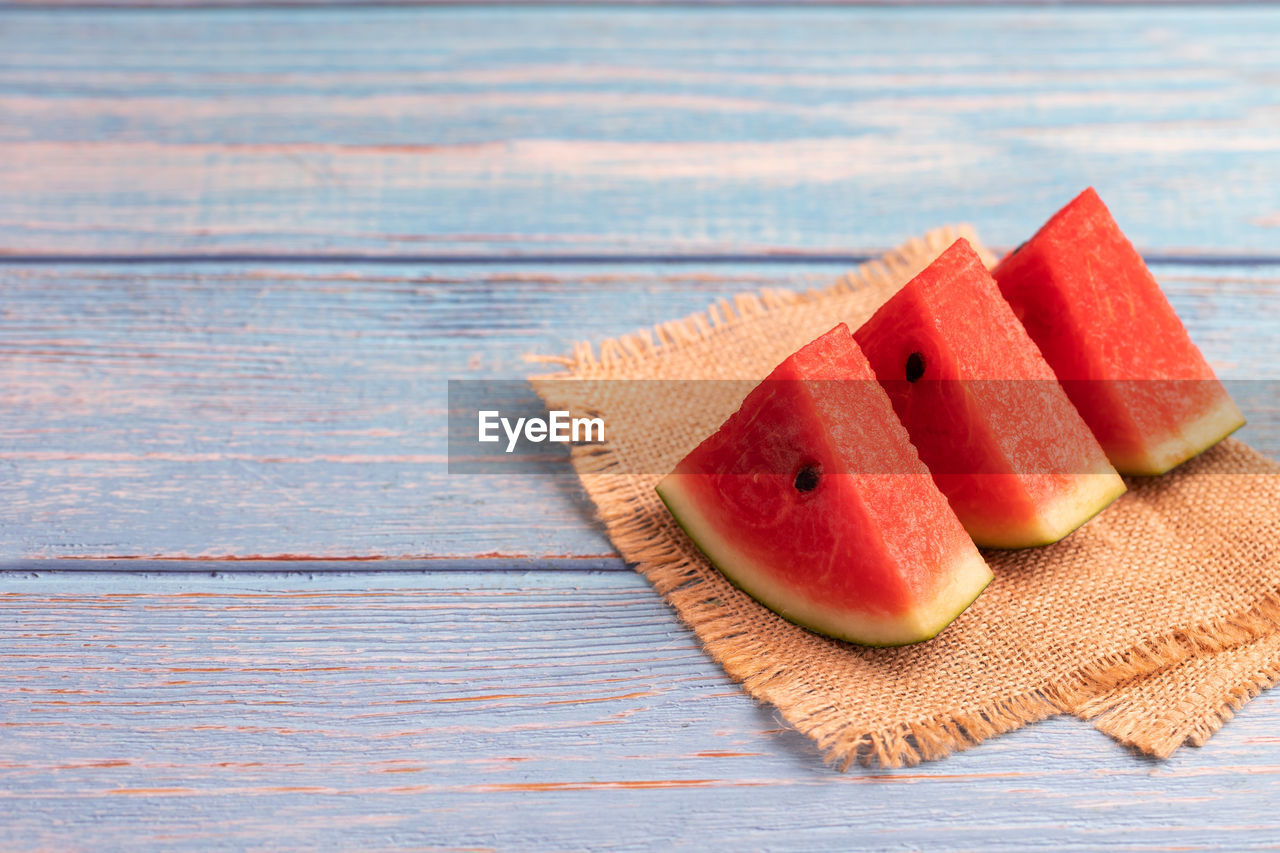 3 pieces of juicy watermelon on a wooden table.