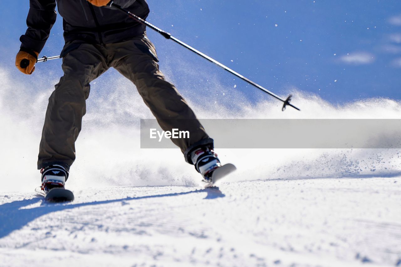 low section of man skiing on snow covered landscape