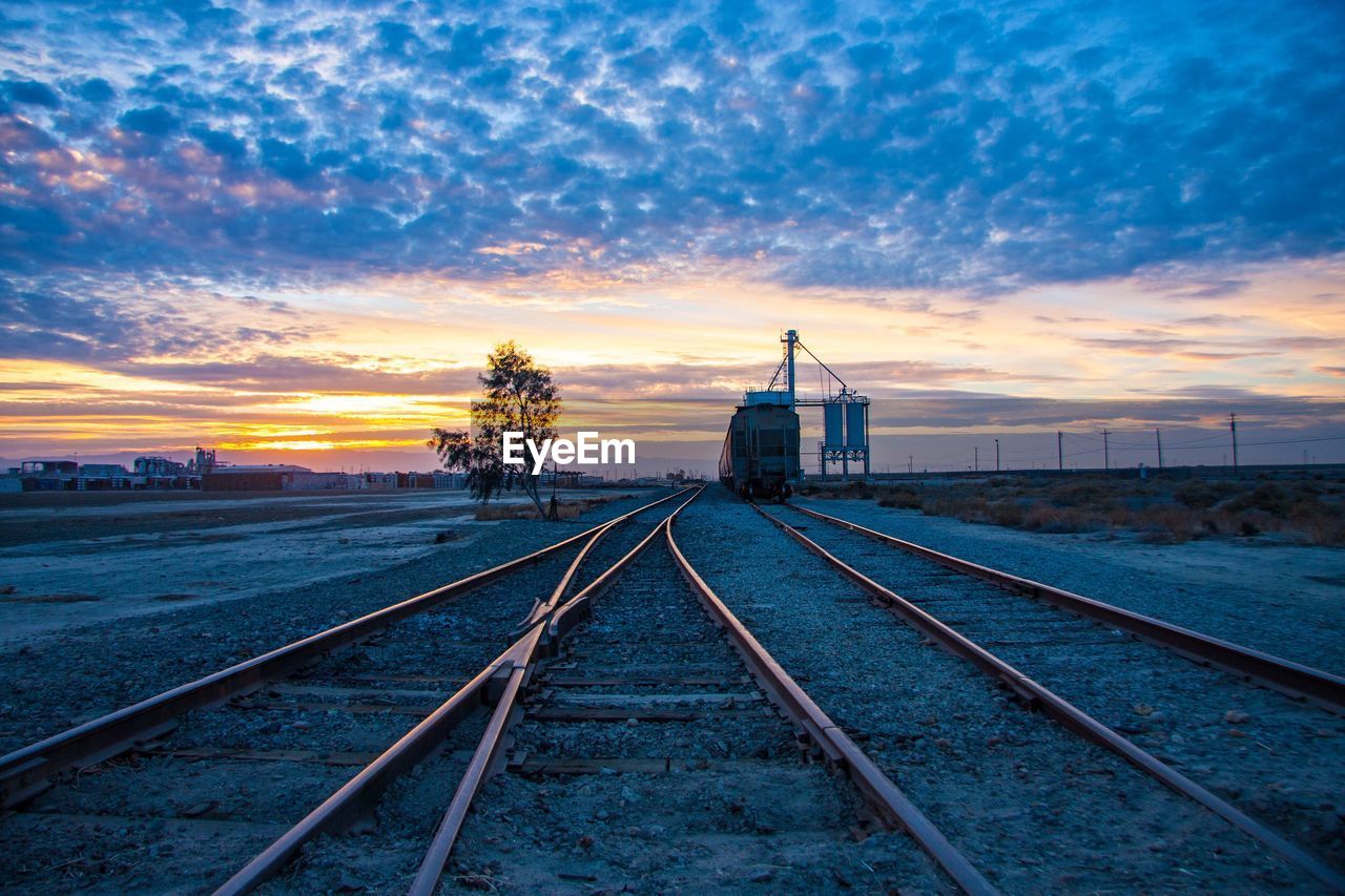 Vanishing point railroad tracks against sky