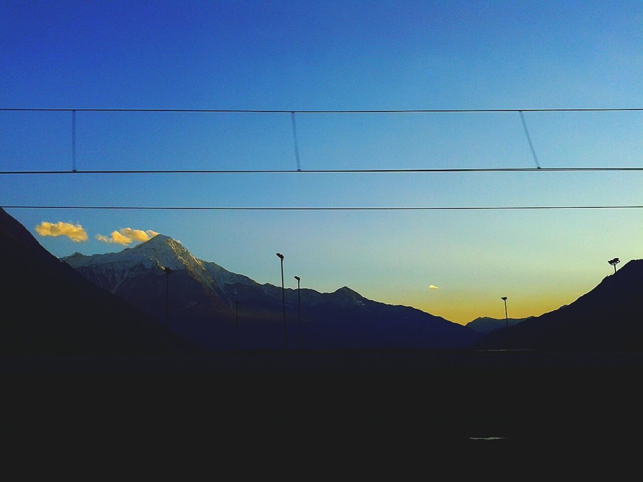 Power cables against mountainous sky