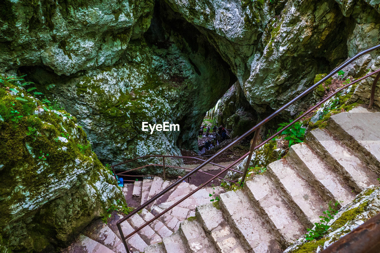 High angle view of narrow stairs along moss rocks