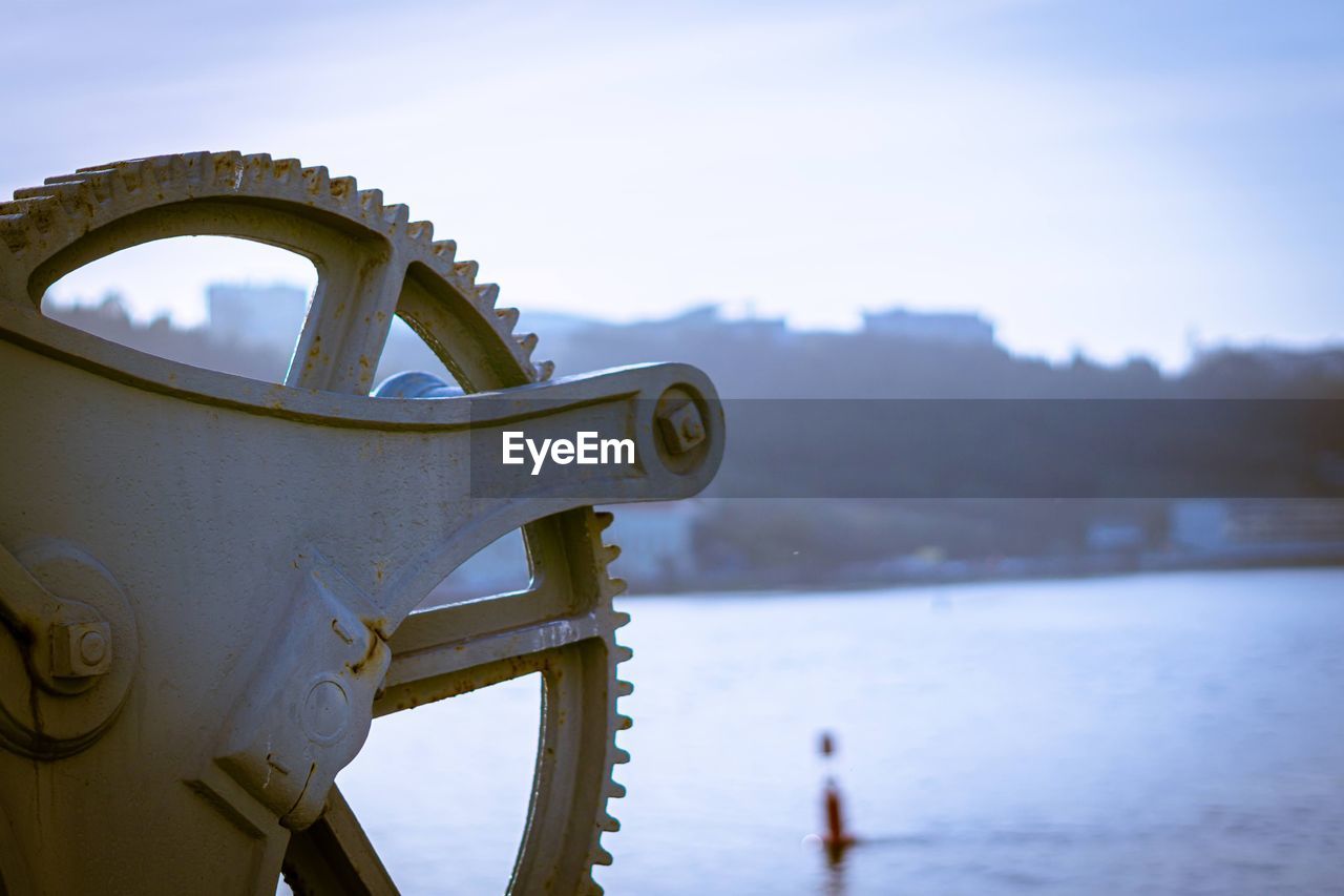 Close-up of metal chain on river against sky