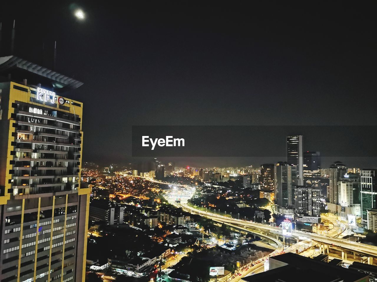 HIGH ANGLE VIEW OF ILLUMINATED BUILDINGS IN CITY AGAINST SKY