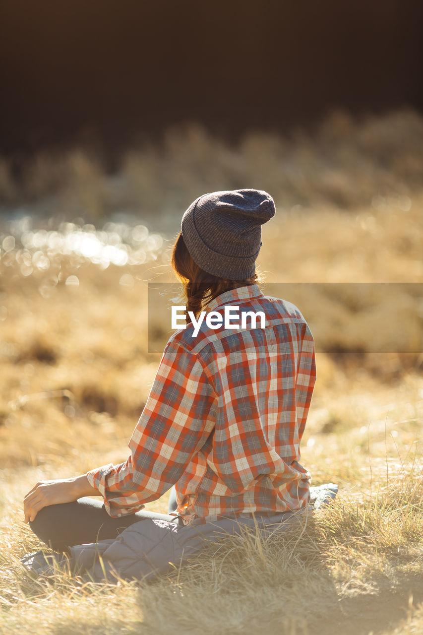 Rear view of woman sitting on field