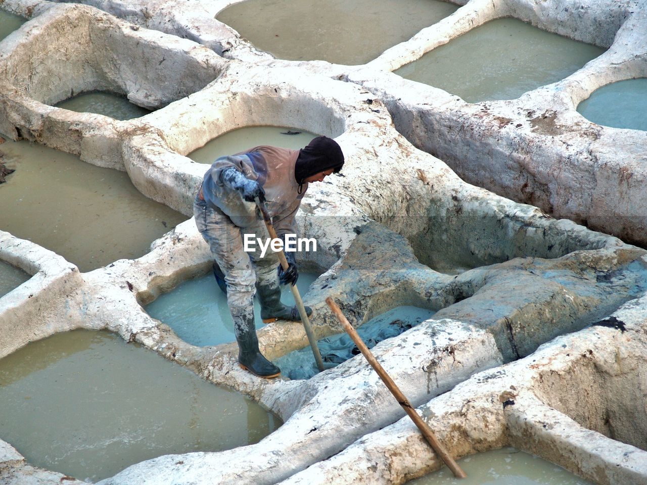 HIGH ANGLE VIEW OF DOG STANDING ON ROCK AGAINST WATER