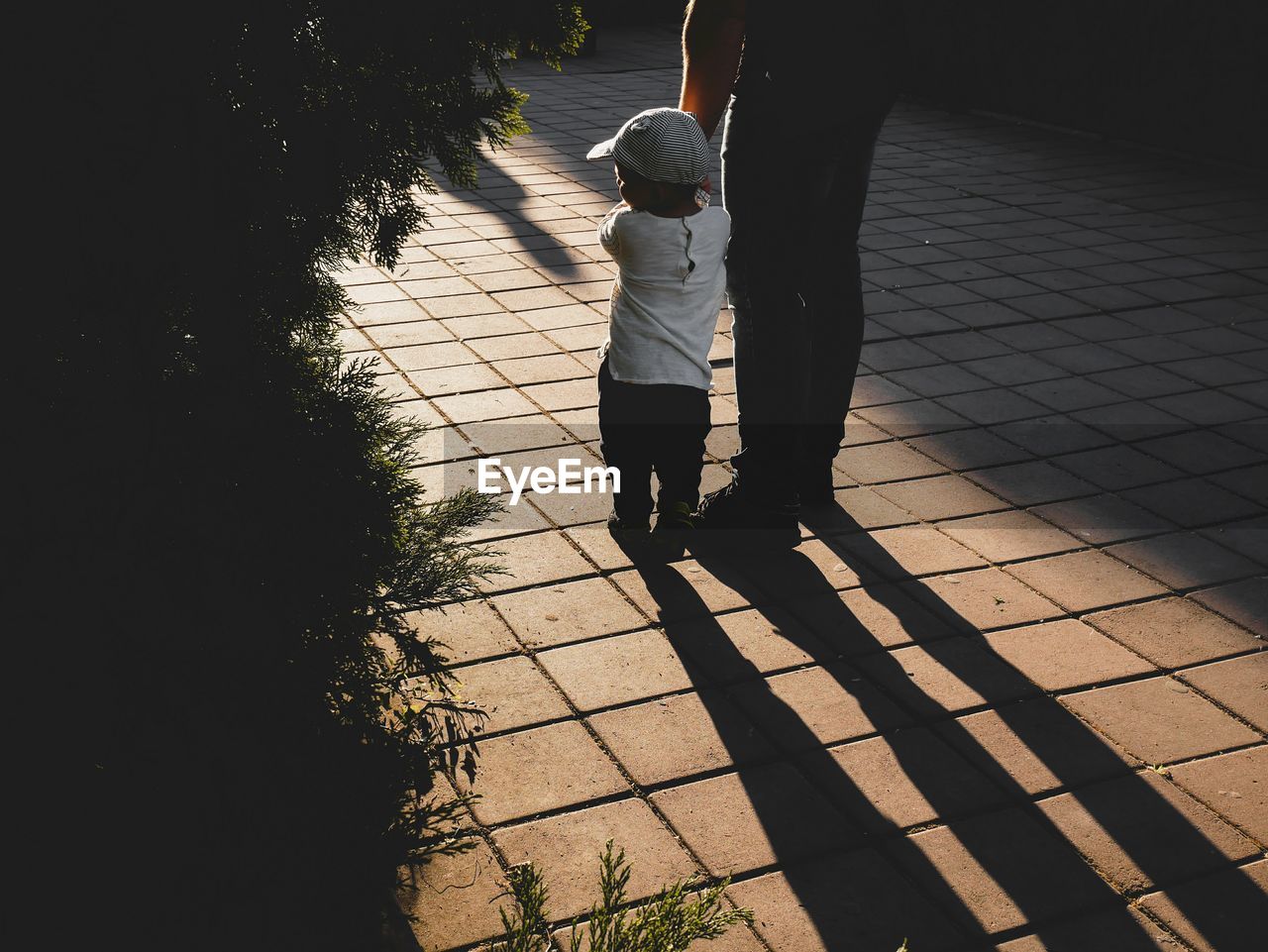 Low section of father standing with son on footpath