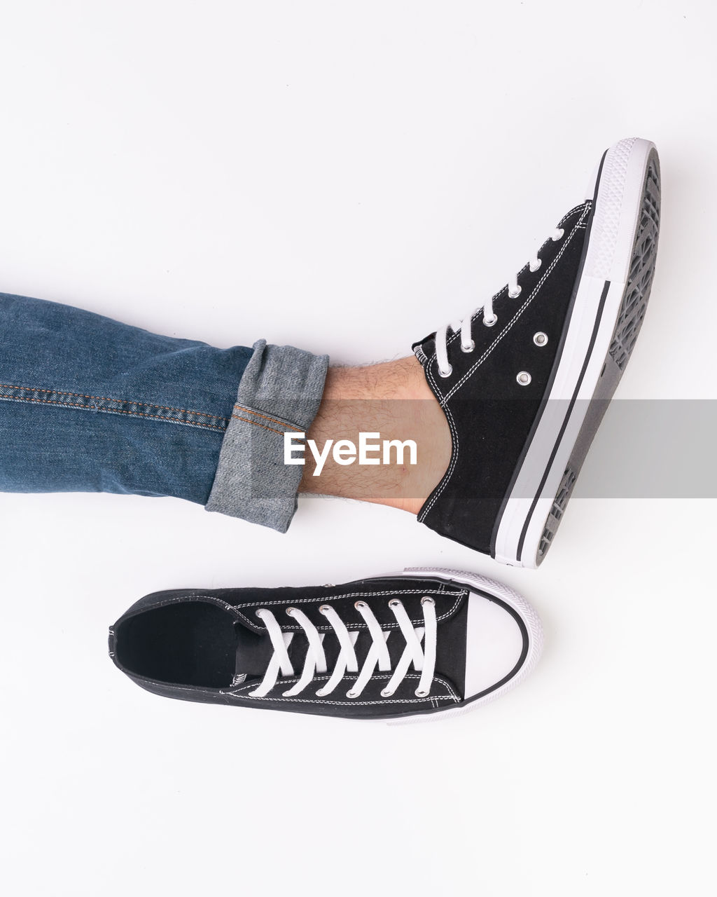 Low section of man wearing canvas shoe against white background